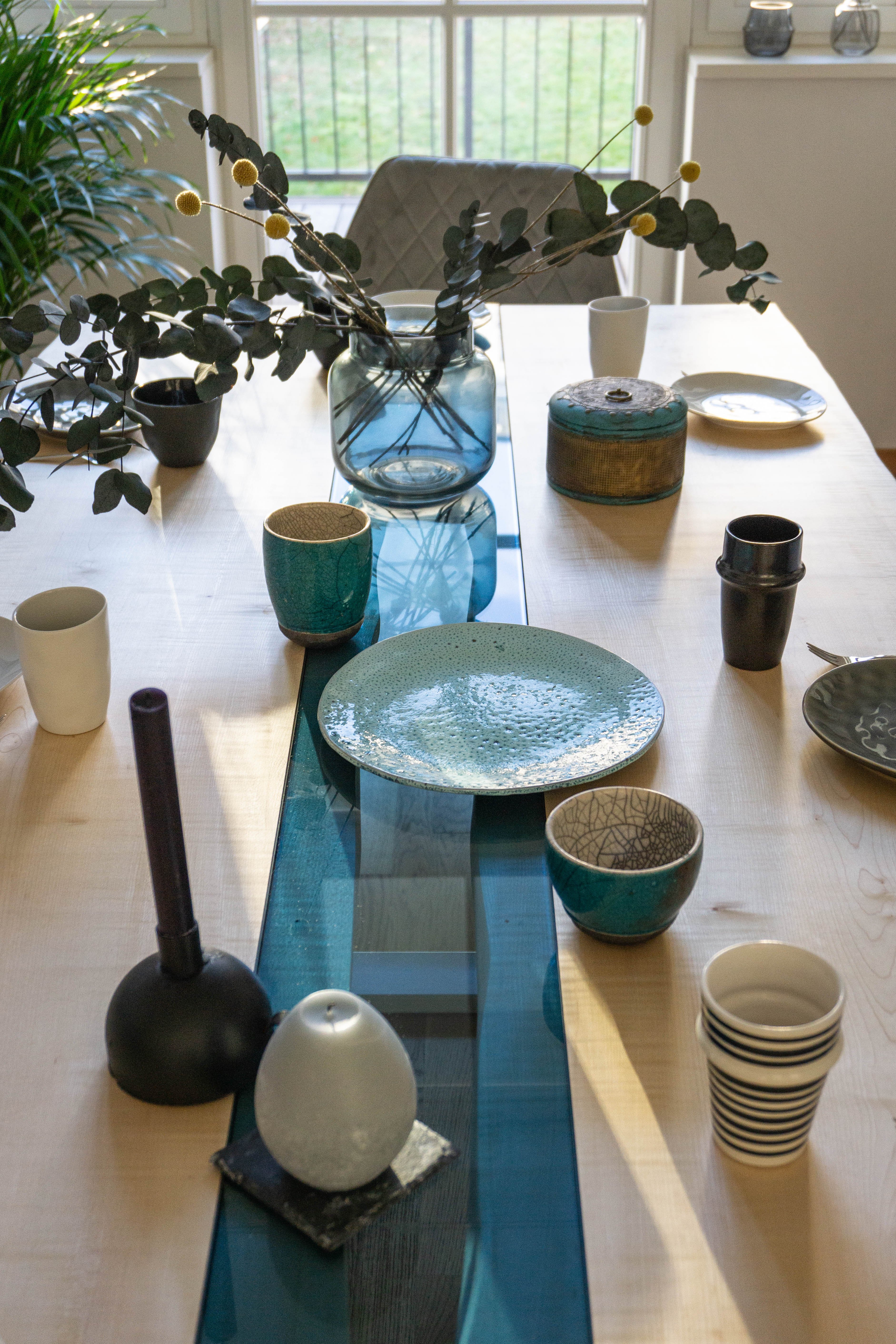 Helle Ahornholzplatte des Esstisches mit modernem, blauem Glaseinsatz