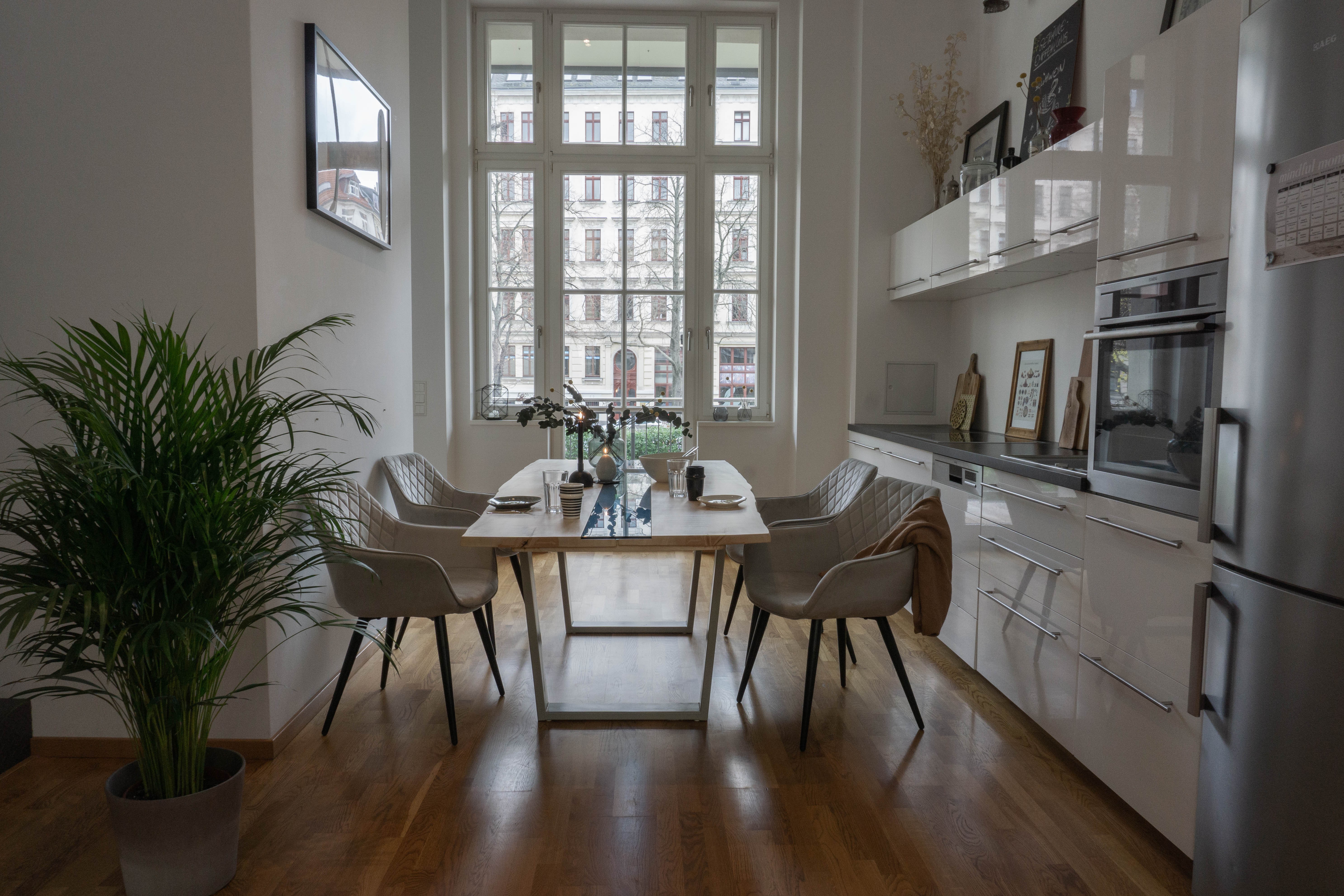 Ansicht des Ahorn-Esstisches mit weißem Stahlgestell und blauem Sicherheitsglas